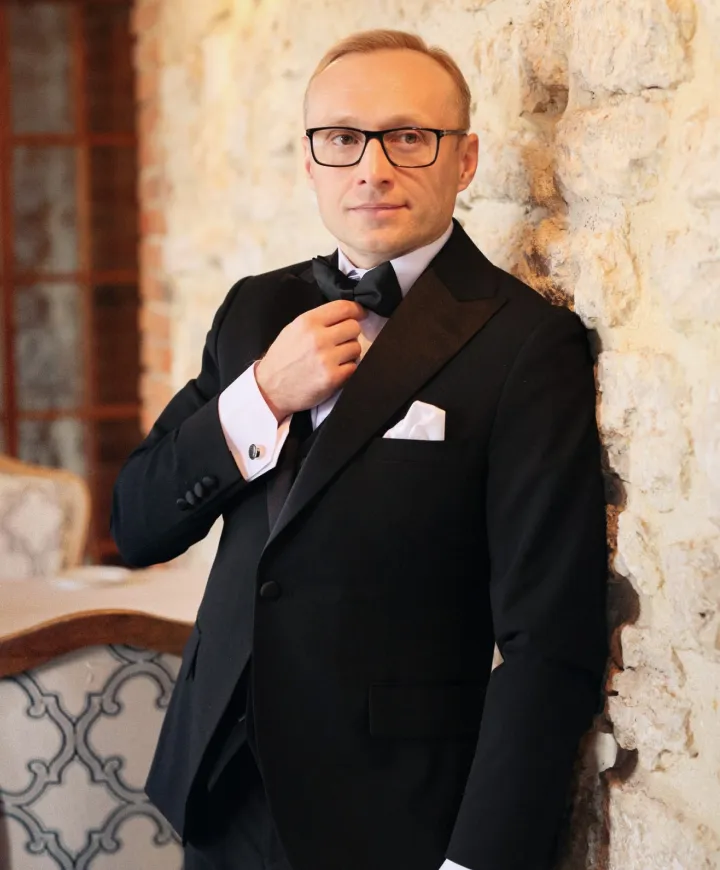 Роман Седов в смокинге у каменной стены